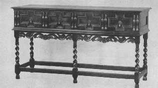 This Jacobean buffet is finely reproduced with the
exception of the spiral carving of the legs, which is too sharp and
thin, and gives the appearance of inadequate support. The split spindle
ornament was much used on furniture of the period.