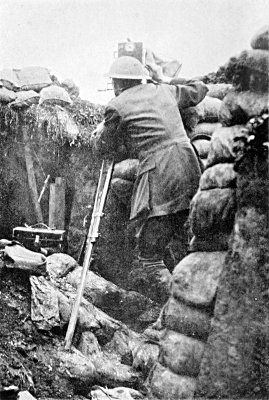 FILMING THE PRELIMINARY BOMBARDMENT OF THE BIG PUSH, JULY 1ST,
1916. A FEW MINUTES AFTER THIS PHOTOGRAPH WAS TAKEN A SHELL
BURST WITHIN SIX YARDS, SMASHING DOWN THE TRENCH WALLS AND
HALF BURYING ME. NOTE THE SANDBAG ON A WIRE IN FRONT OF MY
CAMERA FOR "CAMOUFLAGE"